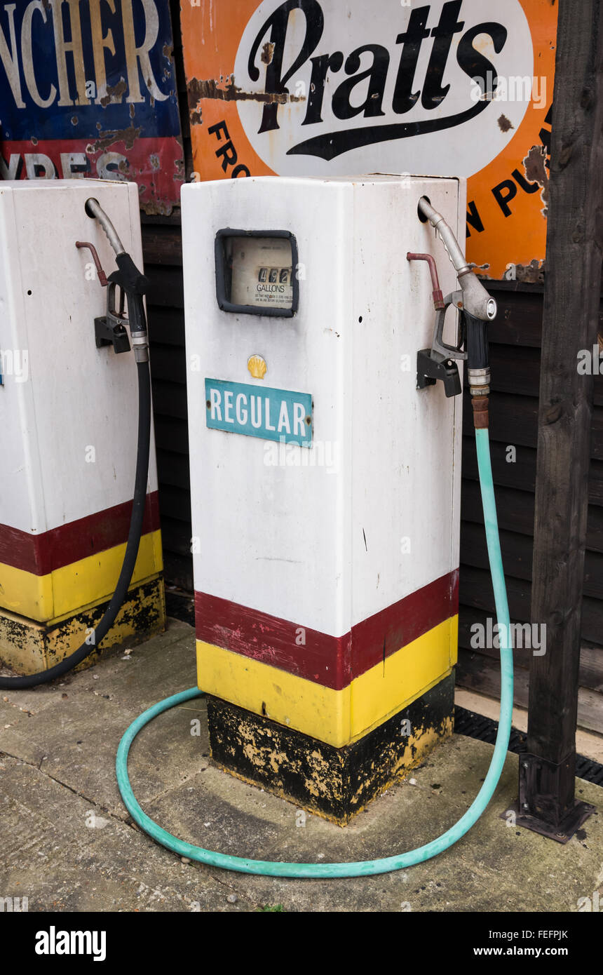 Vintage Benzin / Gas Pumpe bei Battlesbridge Motorcycle Museum in Essex, UK, mit Retro-Werbeschilder im Hintergrund. Stockfoto