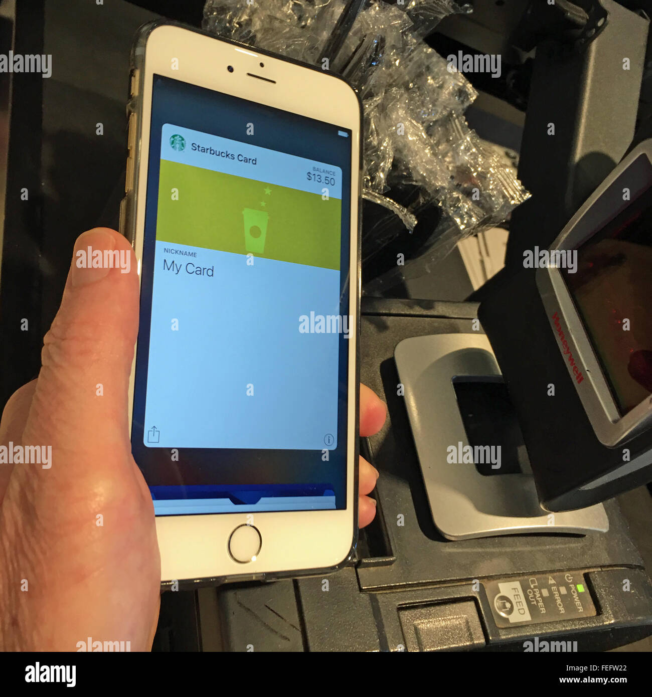 Man zahlt für Kaffee mit seinen Starbucks-Karte innerhalb der Apple Pay Wallet-app auf seinem iPhone 6 s Plus. Stockfoto