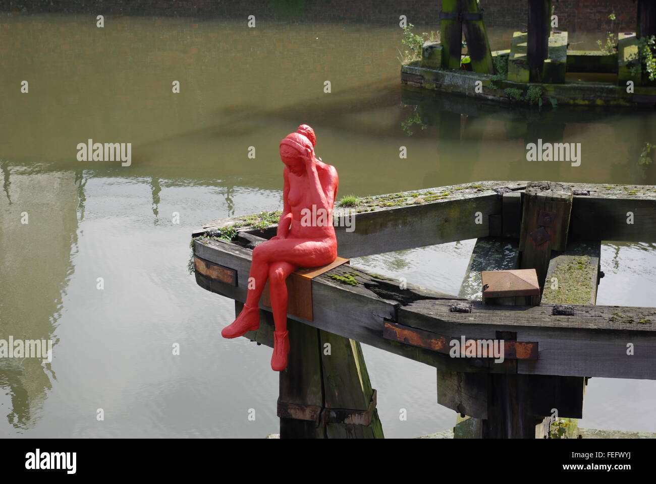 Rote Skulptur nackte Mädchen tragen Kopfhörer und Stiefel, sitzen über dem Fluss Leie in Gent. Stockfoto