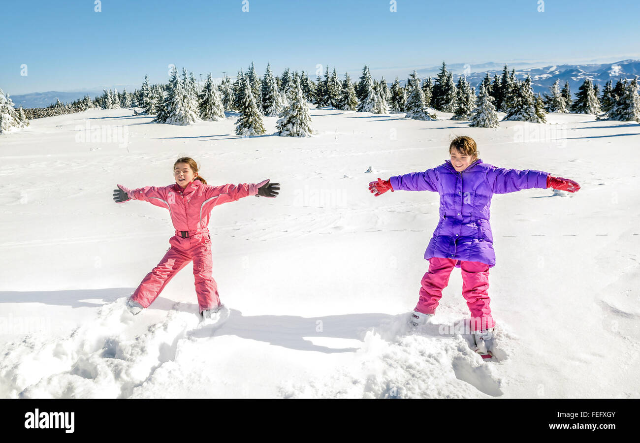 Zwei kleine Mädchen fallen und Spaß auf dem Schnee Stockfoto