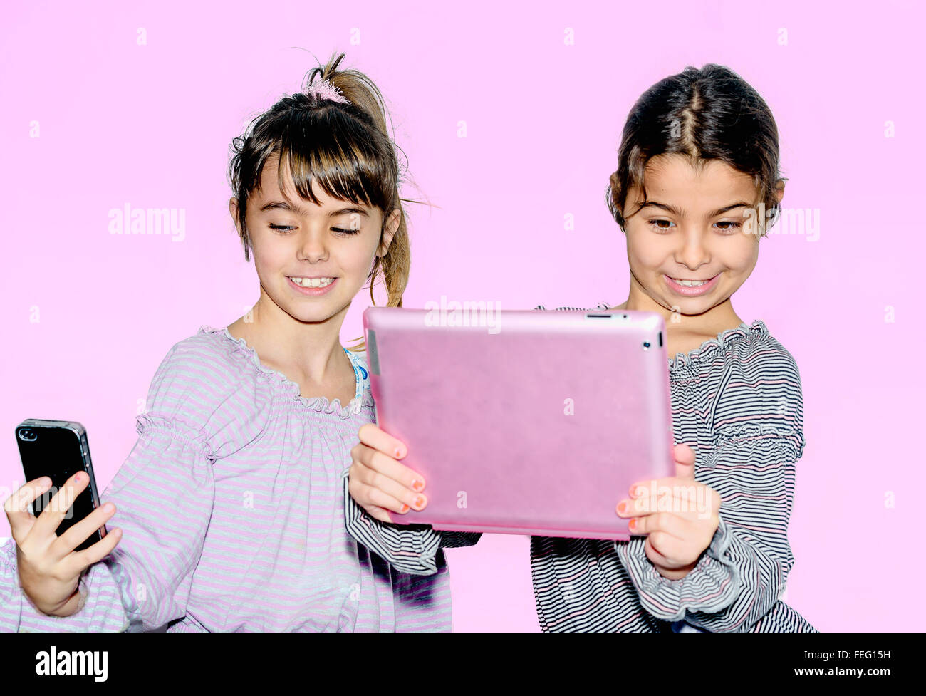 Niedliche kleine Mädchen machen Selfie mit Tablet isoliert auf rosa Stockfoto