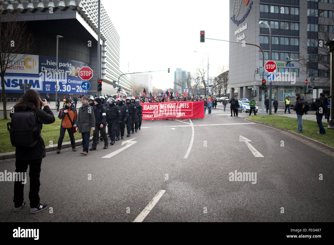 Dresden, Deutschland. 6. Februar 2016. Eine Frau, die Aufnahme von Fotos während Demonstranten halten rote banner zu Fuß auf der Straße bei Protest in Deutschland. © Michael Trammer/Pacific Press/Alamy Live-Nachrichten Stockfoto