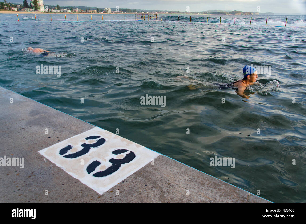 Mit einer großen Zahl von 33 auf dem Poolrand schwimmen die Menschen in einem Meerpool am Collaroy Beach in Sydney, New South Wales, Australien Stockfoto