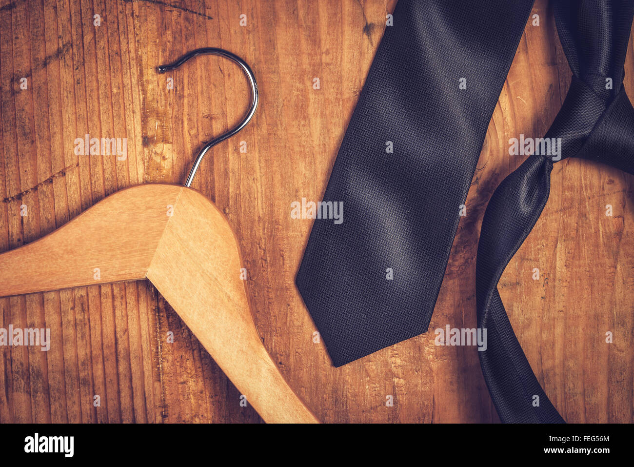 Elegante schwarze Krawatte und Kleiderbügel, modischen männlichen Business Anzug Tagesordnungspunkt Schreibtisch aus Holz. Stockfoto