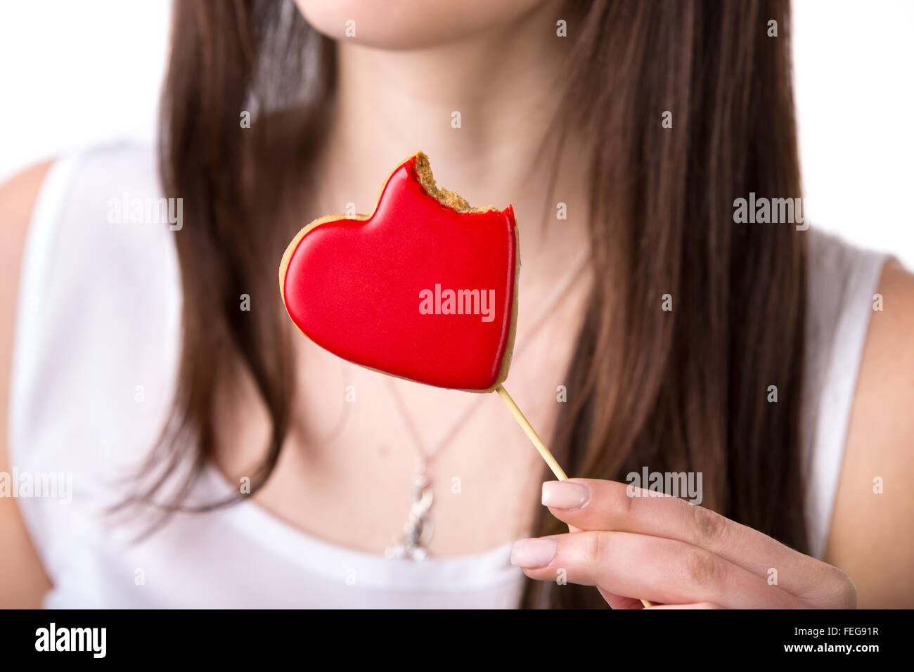 Nahaufnahme von köstlichen Herz Form rot Cookie mit Biss, junge schöne Frau mit gebissen aus Biskuit, Studio Stockfoto