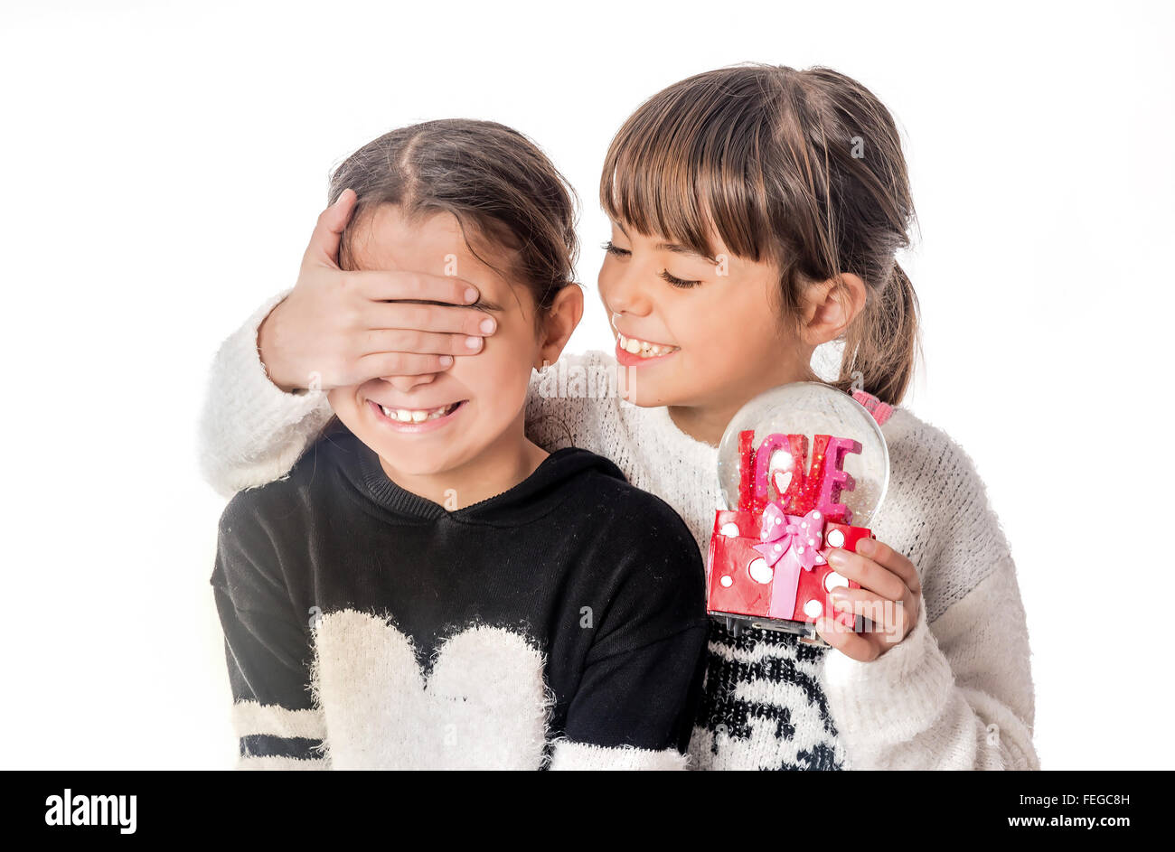 Kleines Mädchen geben Liebe Überraschungsgeschenk zu ihrer Freundin mit weißem Hintergrund Stockfoto