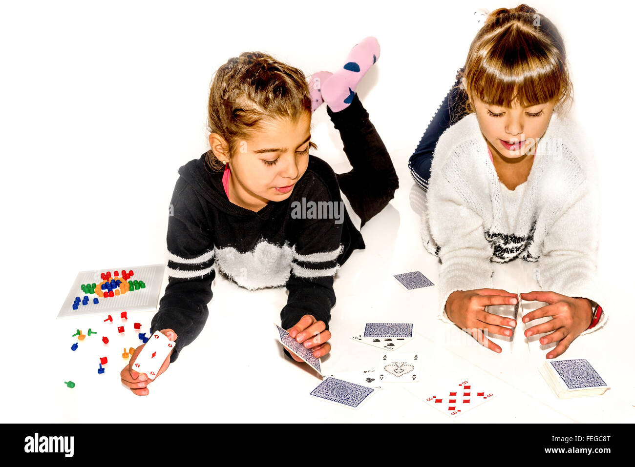 Glückliche kleine Mädchen machen Kartenhaus isoliert auf weiss Stockfoto