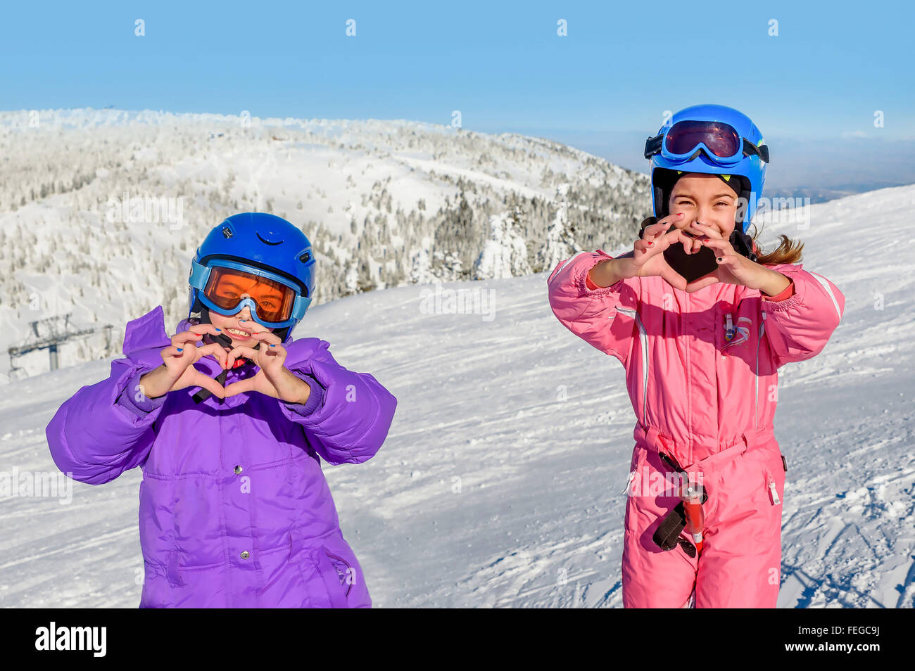 Zwei kleine Mädchen machen Herz mit ihren Händen im Schnee Stockfoto