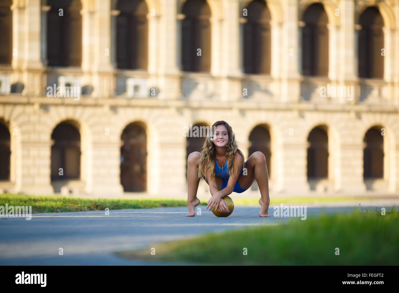 Junge professionelle Turnerin sitzen mit einem Ball auf der Straße Stockfoto