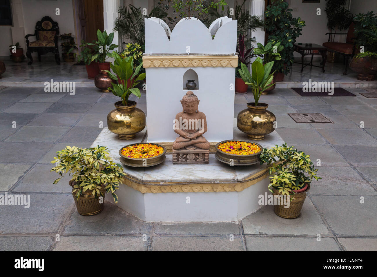 Ein Alter für Buddha umgeben mit Pflanzen und Blumen. Stockfoto