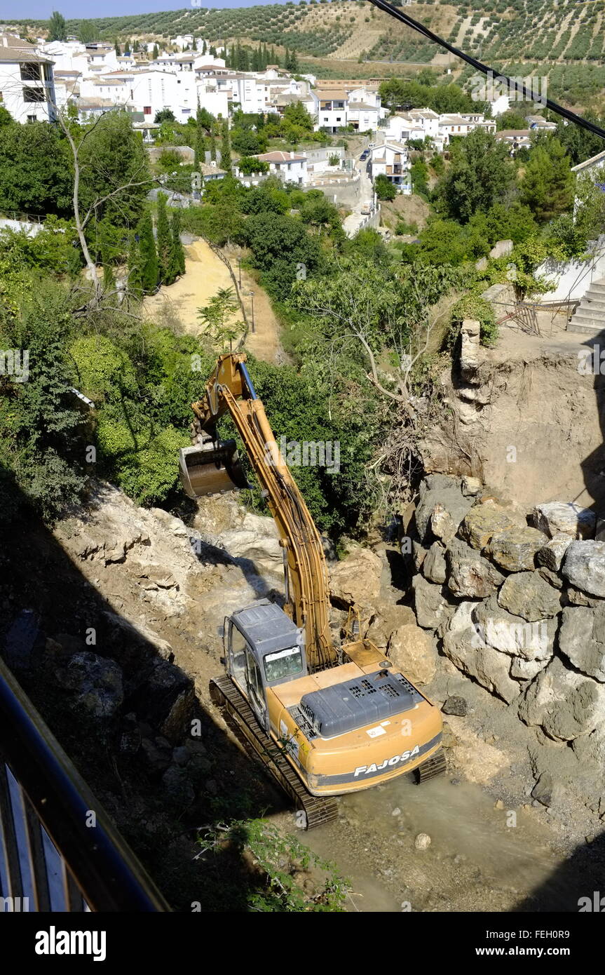 Digger senkte in einem Flussschlucht, entfernen oder neu Website Felsen von Flut spülte. Erlangen, Cordoba. Spanien Stockfoto