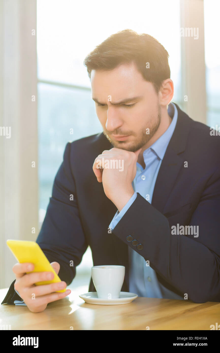 Hübscher Mann sucht besorgt starrte auf seinem Smartphone. Stockfoto