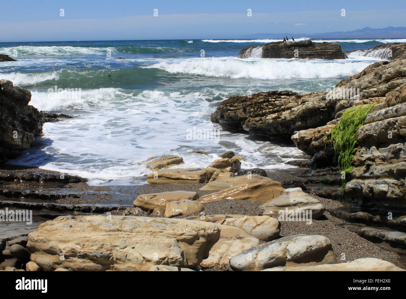 Wellen an den Felsen. Felsen, die auf der Suche Sprungbrett ins Wasser, zwei der sieben in einer Reihe Stockfoto