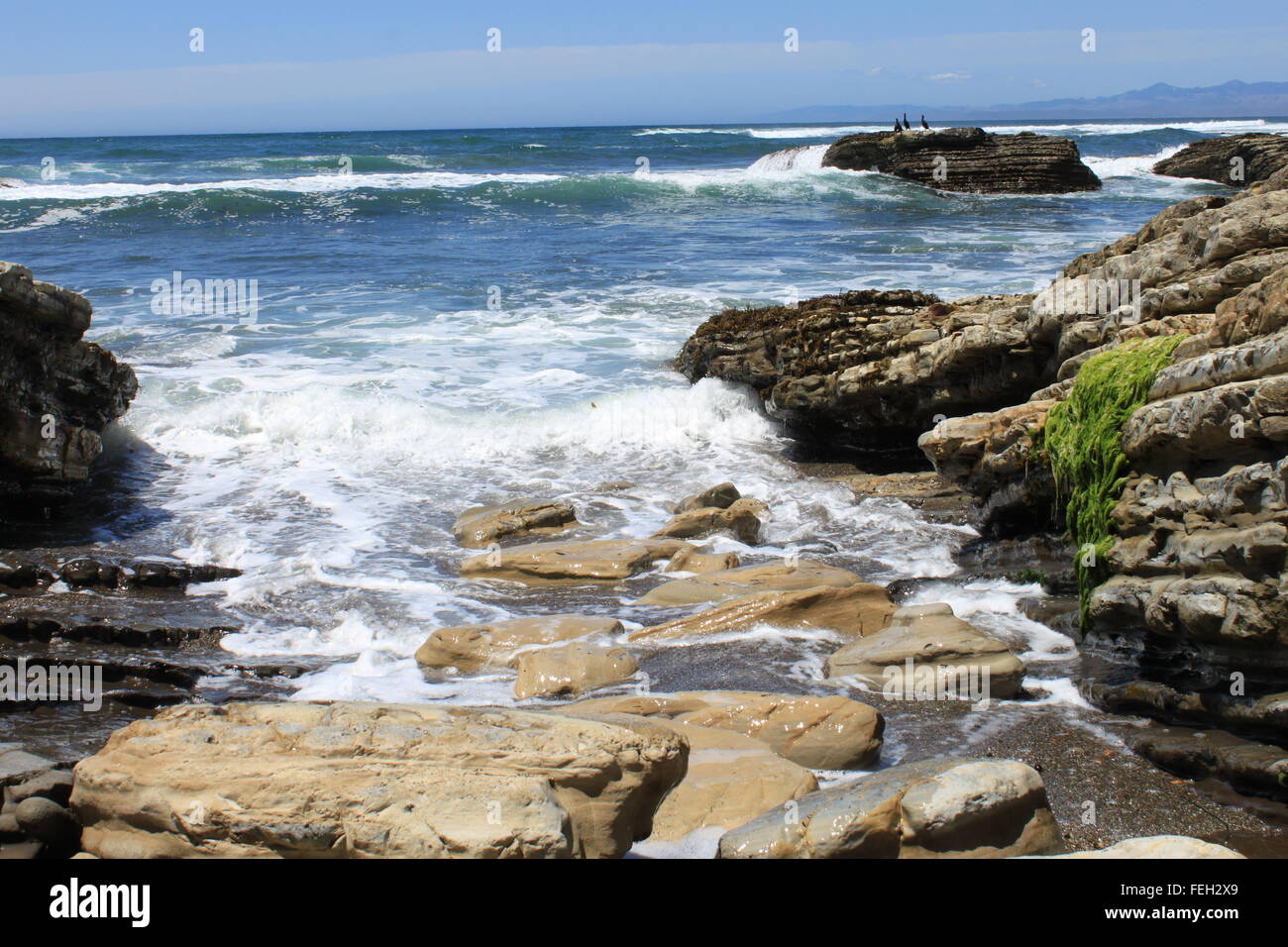 Wellen an den Felsen. Felsen, die auf der Suche Sprungbrett ins Wasser, sieben von sieben in einer Reihe Stockfoto