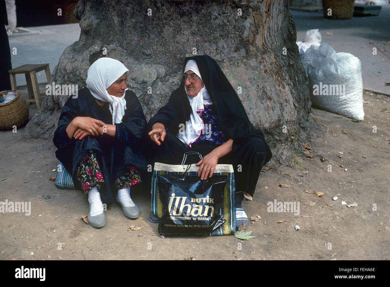 Zwei Generationen von Türkin. Eine traditionelle türkische Frau, gekleidet in traditioneller Tracht Gespräche mit einem jüngeren türkischen Mädchen oder junge Frau unter einer Platane-Bursa-Türkei Stockfoto