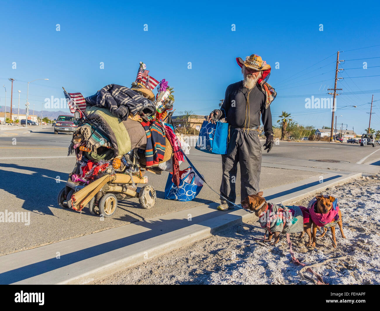 Ein Obdachloser männlichen Charakter und seine beiden Haustier Chihuahuas auf Leinen und seiner überladenen zweirädrigen Karren mit seinem hab und gut. Stockfoto