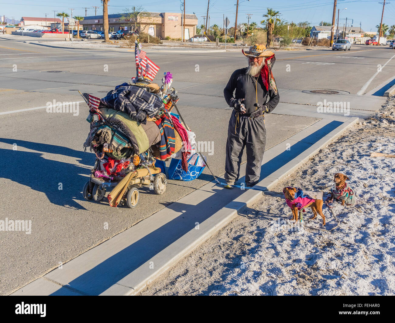 Ein Obdachloser männlichen Charakter und seine beiden Haustier Chihuahuas auf Leinen und seiner überladenen zweirädrigen Karren mit seinem hab und gut. Stockfoto