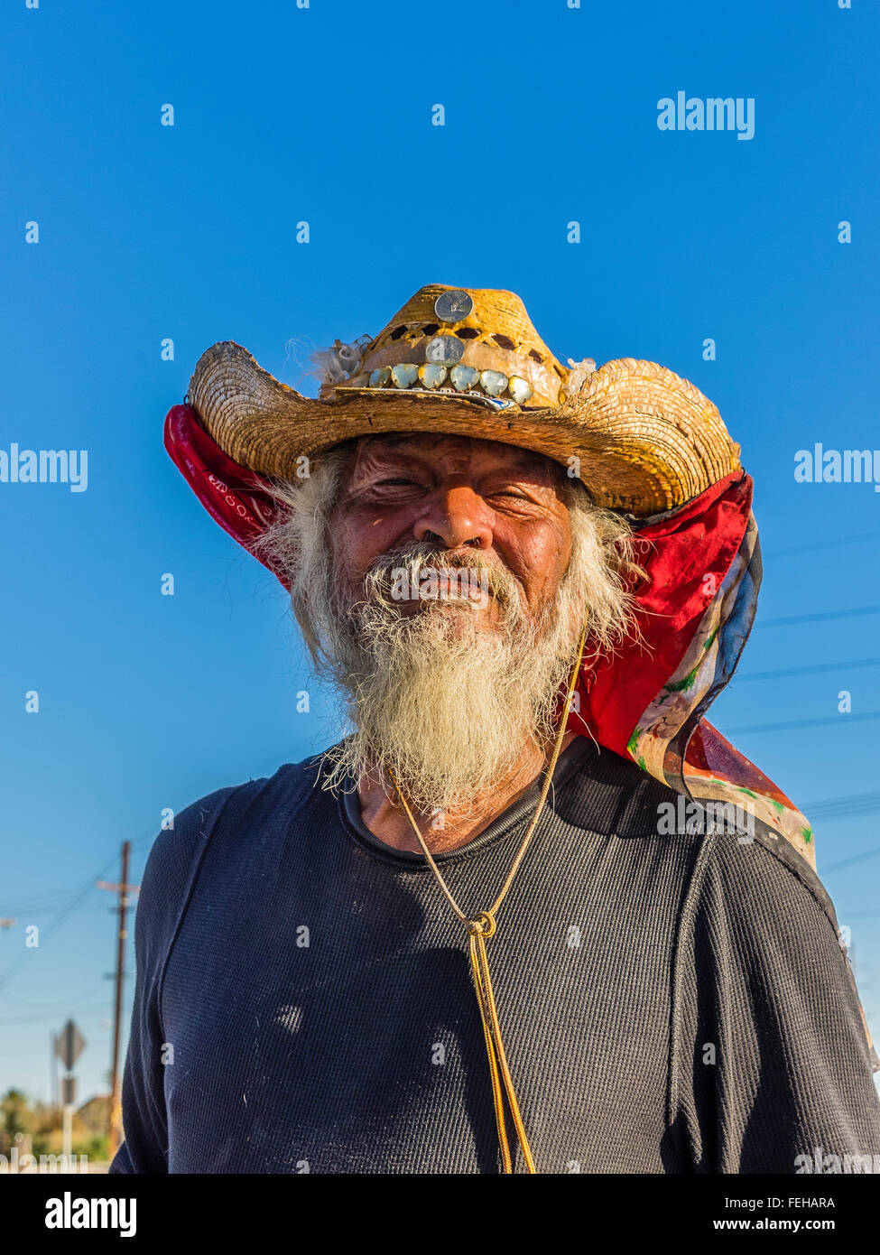 Kopf und Schultern Porträt von einem Obdachlosen männlichen Charakter nach vorne gerichtet und trägt einen geschmückten Strohhut und weißen Bart. Stockfoto