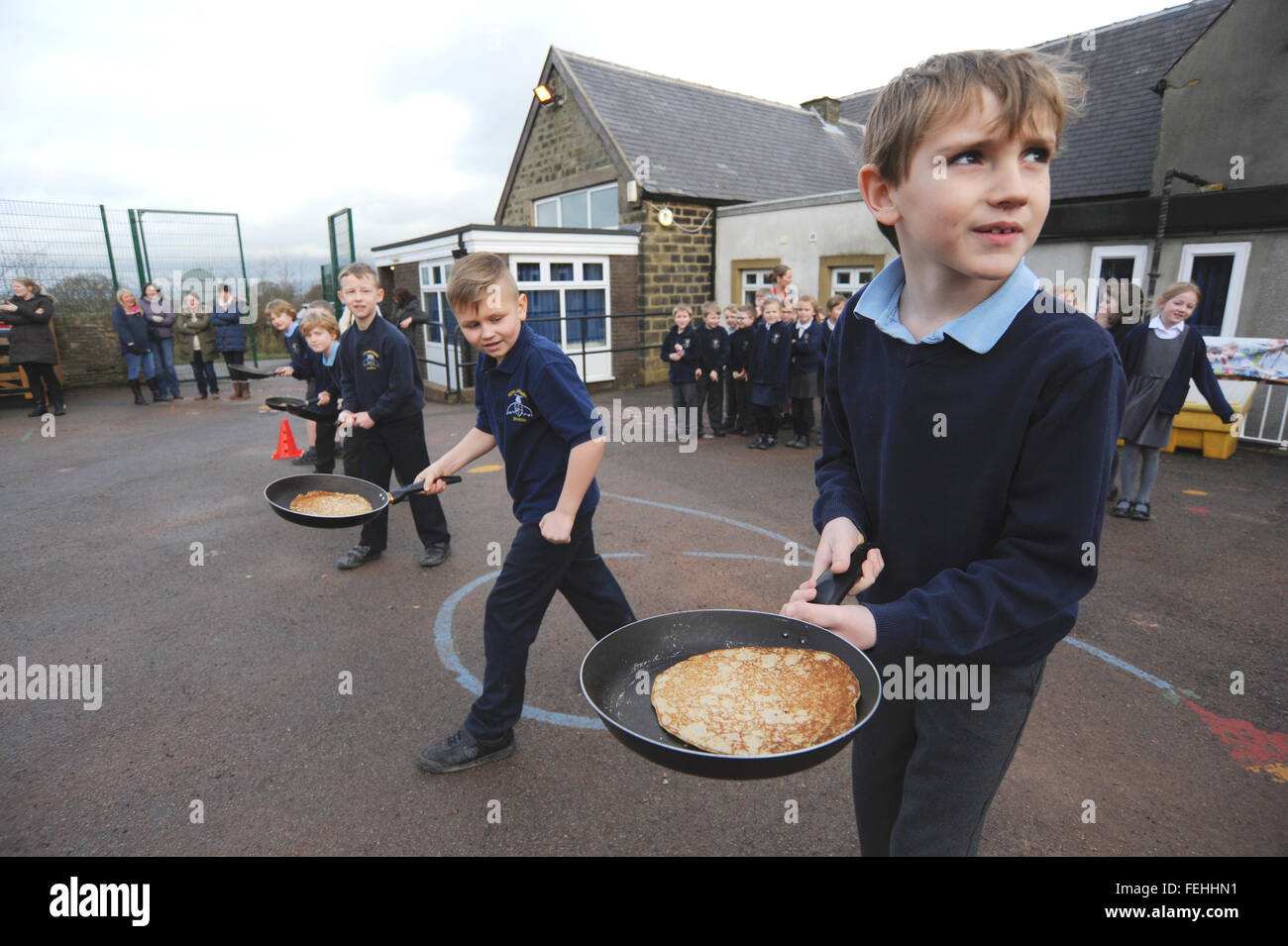 Schule Kinder freuen sich über ein Pfannkuchen-Rennen. Stockfoto