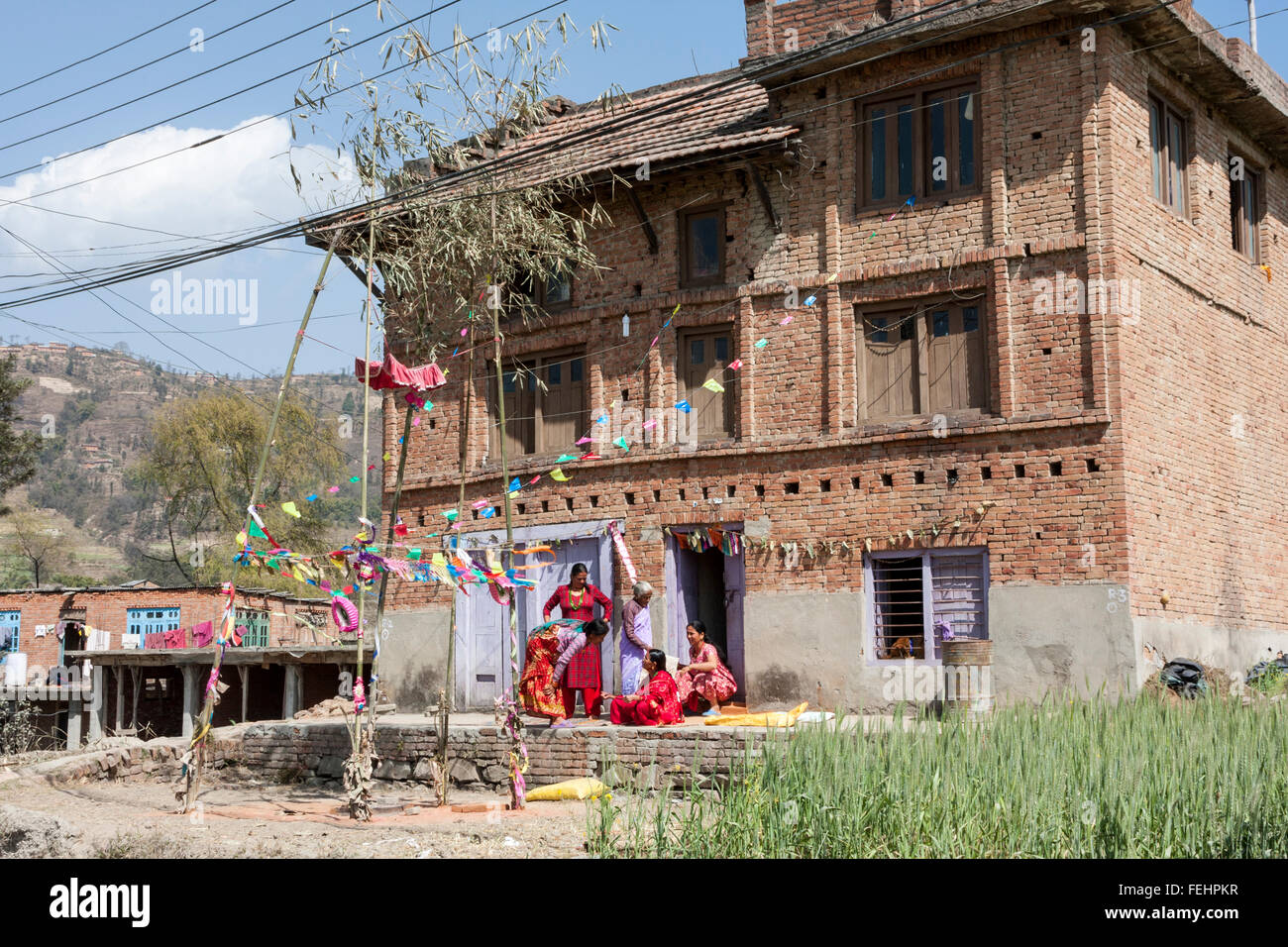 Bhaktapur, Nepal.  Frauen entspannen außerhalb ihres Hauses, dekoriert für eine Hochzeitsfeier. Stockfoto