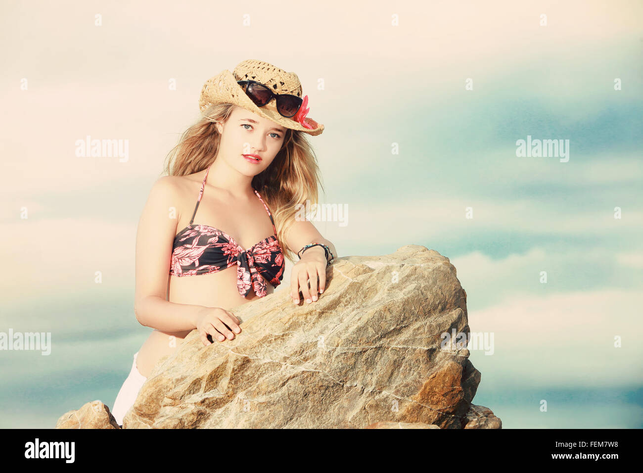 Eine Nahaufnahme Foto einer schönen blonden Dame gekleidet in einem Blumen- oder tropischen Bikini mit Cowboy-Hut und Sonnenbrille sideway gelehnt Stockfoto