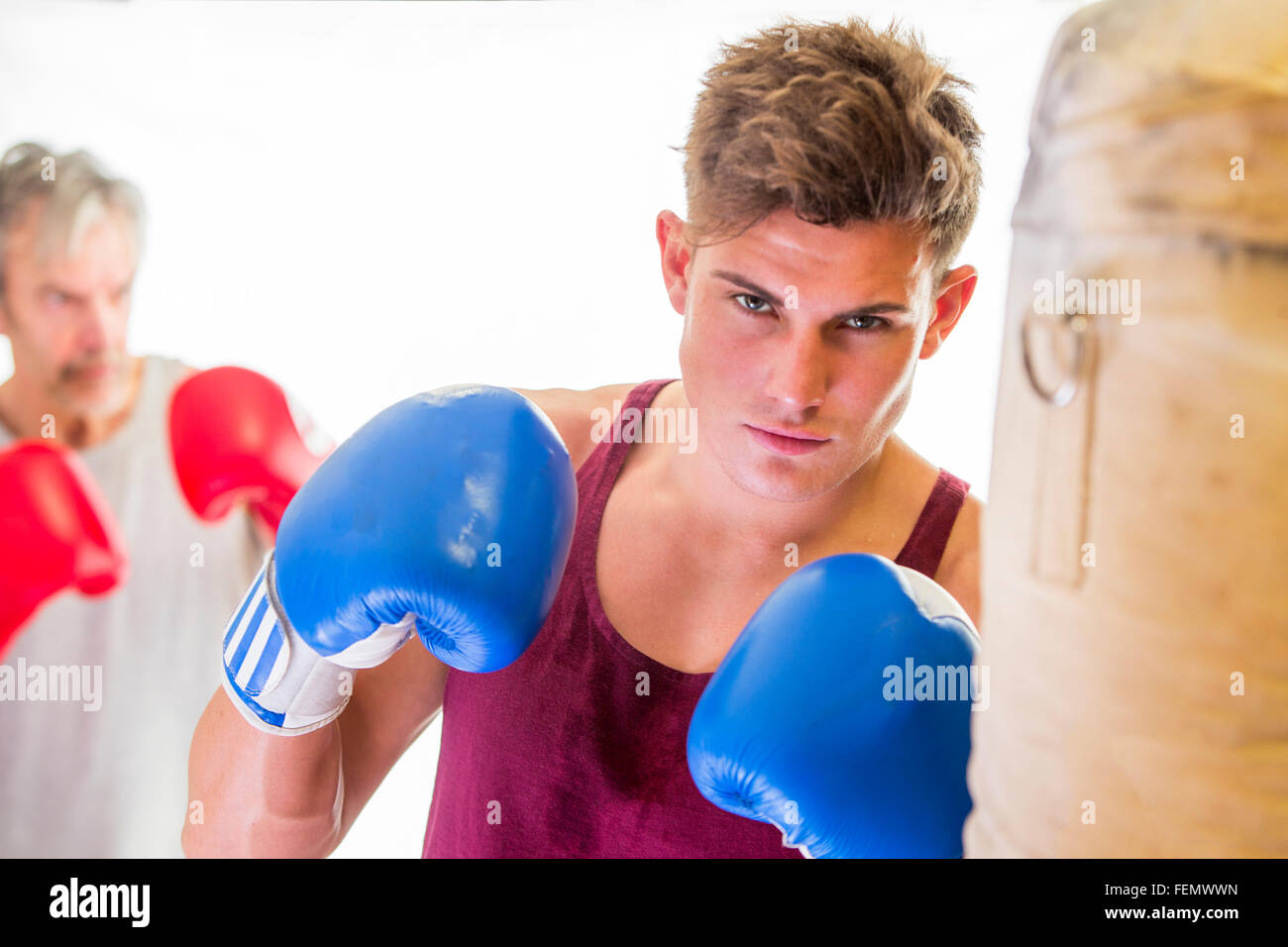 Attraktive junge Mann in einer Haltung der Boxen mit Handschuhen und ein Boxsack Stockfoto