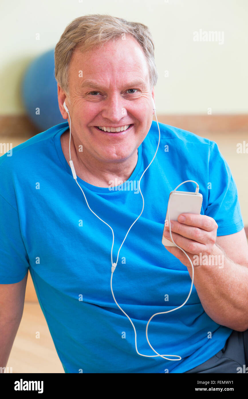 Senior woman entspannen und anhören von Musik nach seinem Training in der Turnhalle Stockfoto