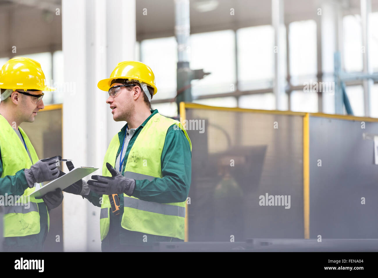 Arbeiter in Schutzkleidung im Gespräch mit Zwischenablage Stockfoto