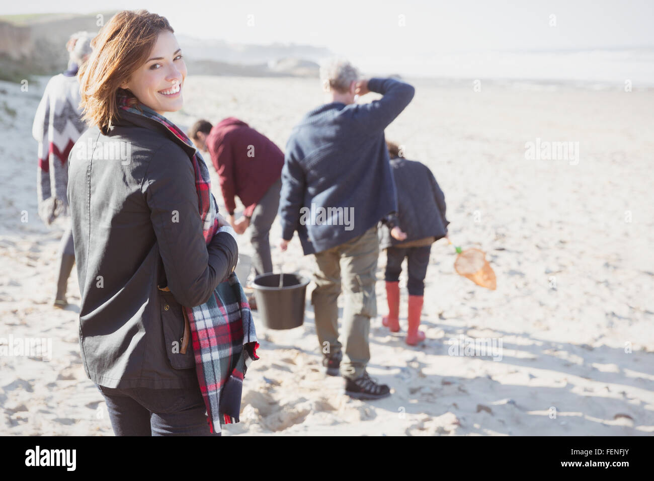 Lächelnde Frau Porträt Wandern am sonnigen Strand mit Familie Stockfoto
