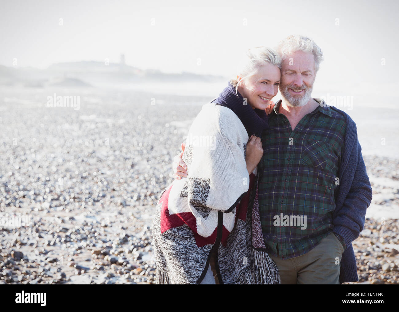 Lächelnde älteres paar zu Fuß am Strand Stockfoto