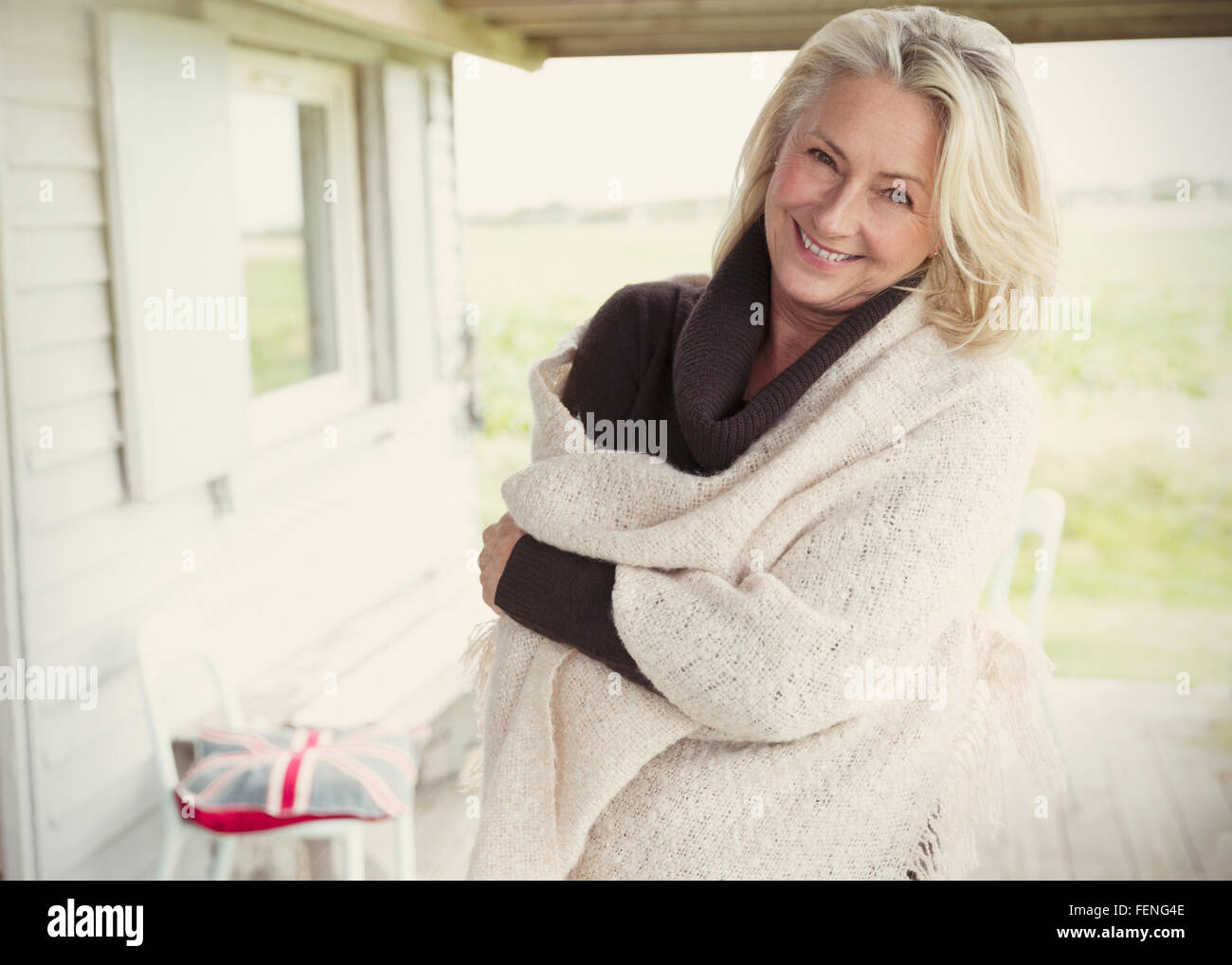 Porträt lächelnd senior Frau trägt Schal auf Veranda Stockfoto