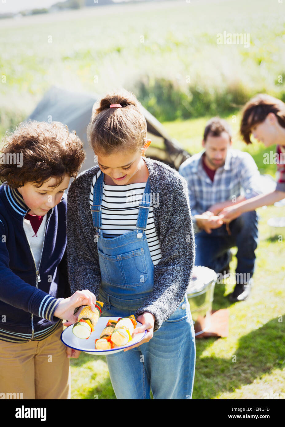 Bruder und Schwester Blick auf Gemüse-Spieße auf sonniger Campingplatz Stockfoto