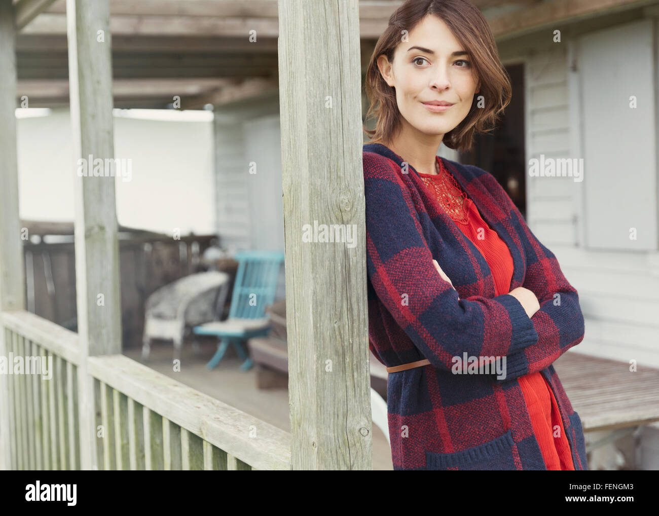 Nachdenkliche Frau in Pullover wegsehen auf Veranda Stockfoto