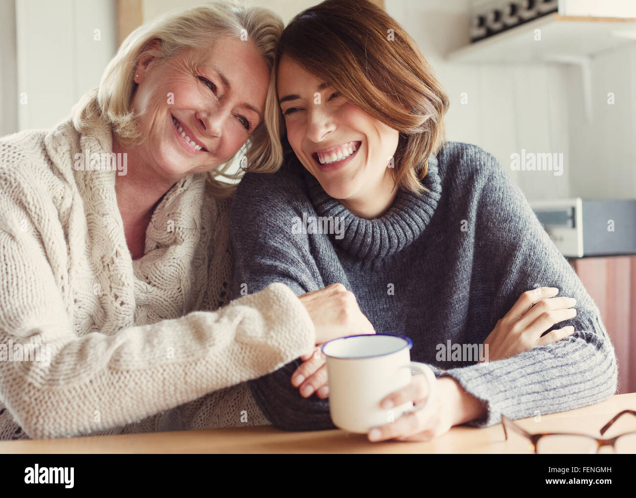 Mutter und Tochter Lachen in Pullover umarmt und Kaffeetrinken Stockfoto