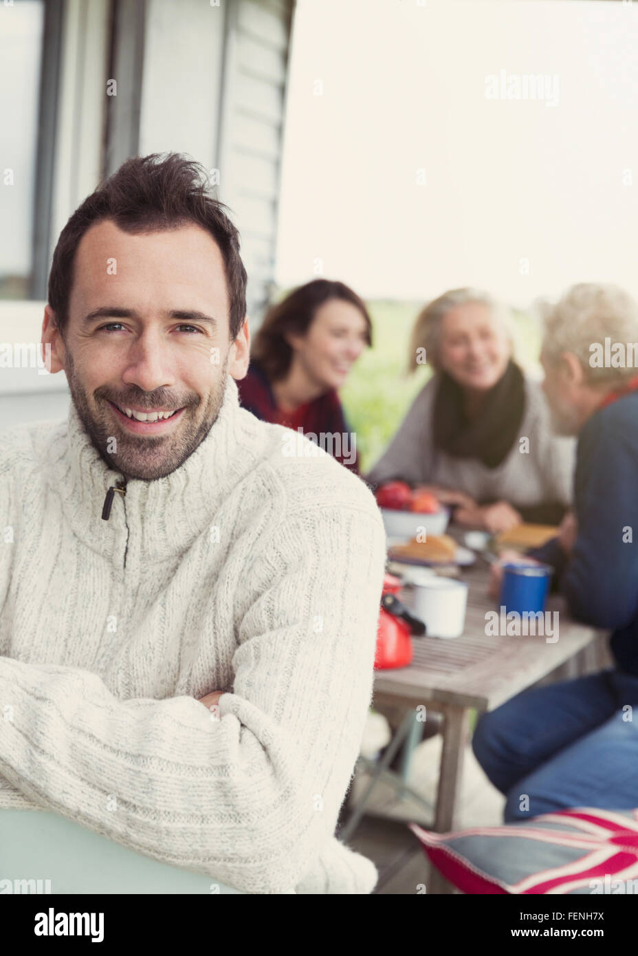 Porträt, Lächeln Brünette Mann im Pullover auf Veranda mit Familie im Hintergrund Stockfoto