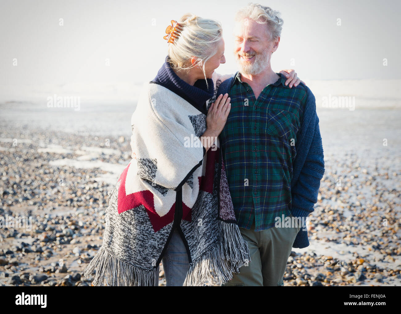 Älteres Paar zu umarmen und zu Fuß auf sonnigen felsigen Strand Stockfoto