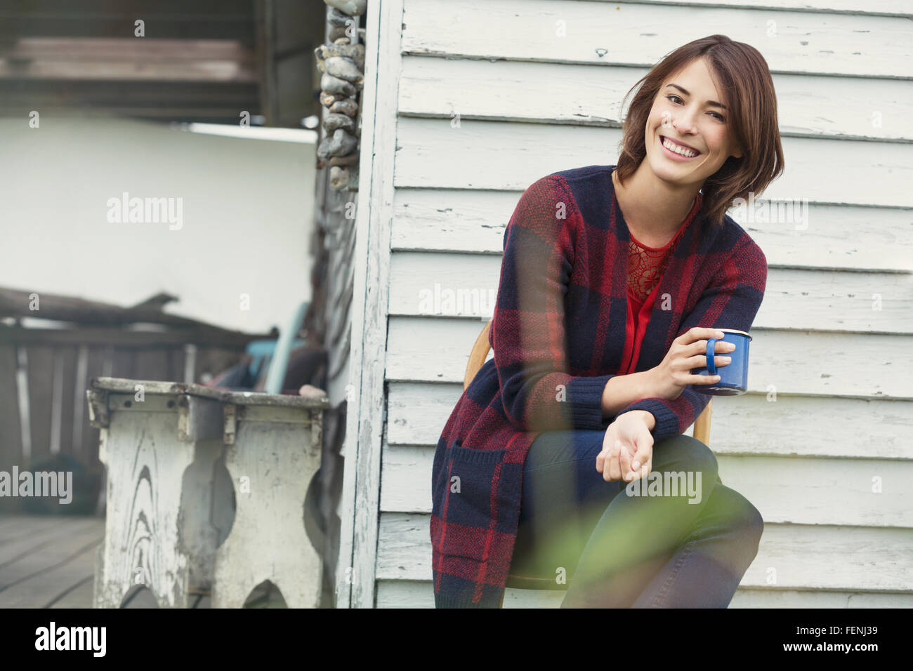Porträt lächelnde Brünette Frau Kaffeetrinken auf Veranda Stockfoto