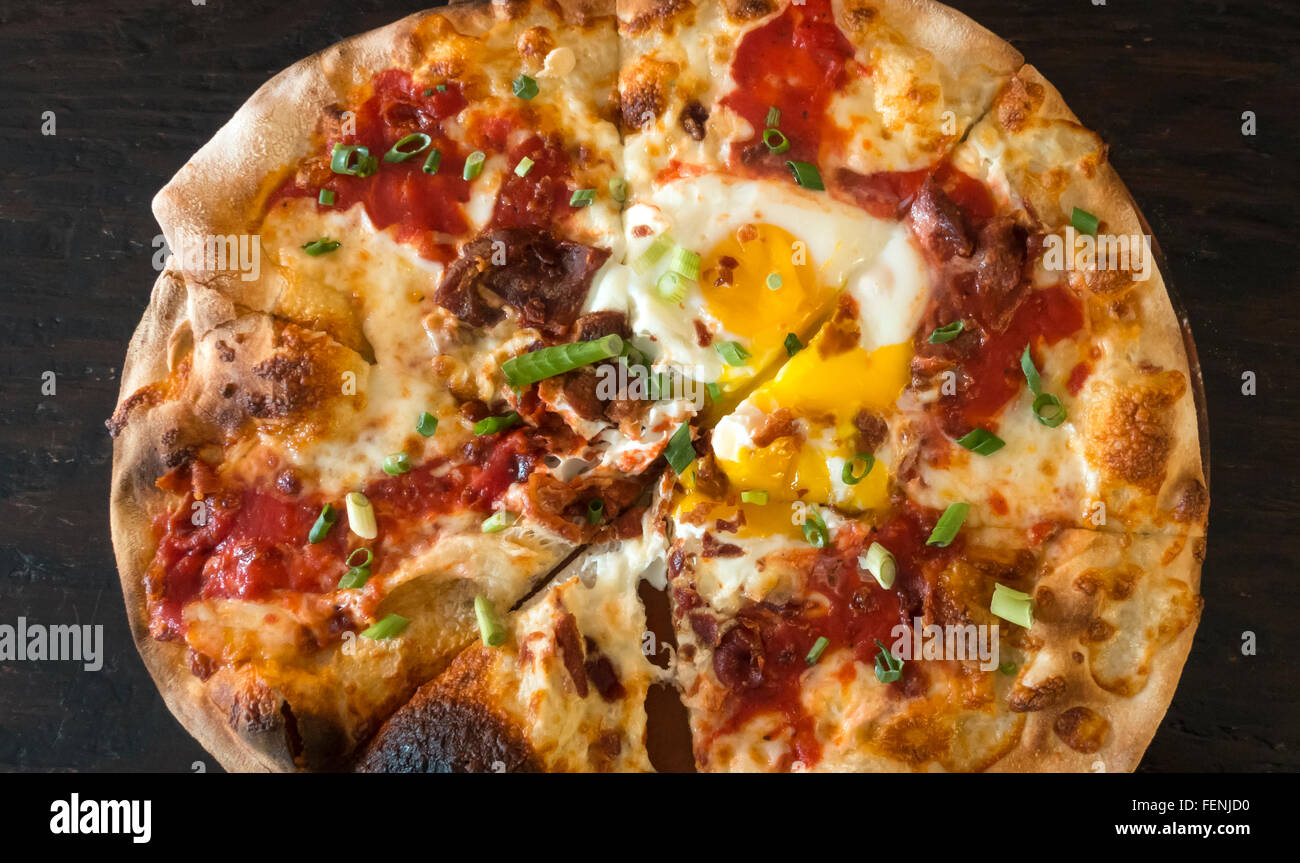 Frühstück Pizza mit Mozzarella, Tomaten, Speck, Wurst und zwei Spiegeleier Stockfoto