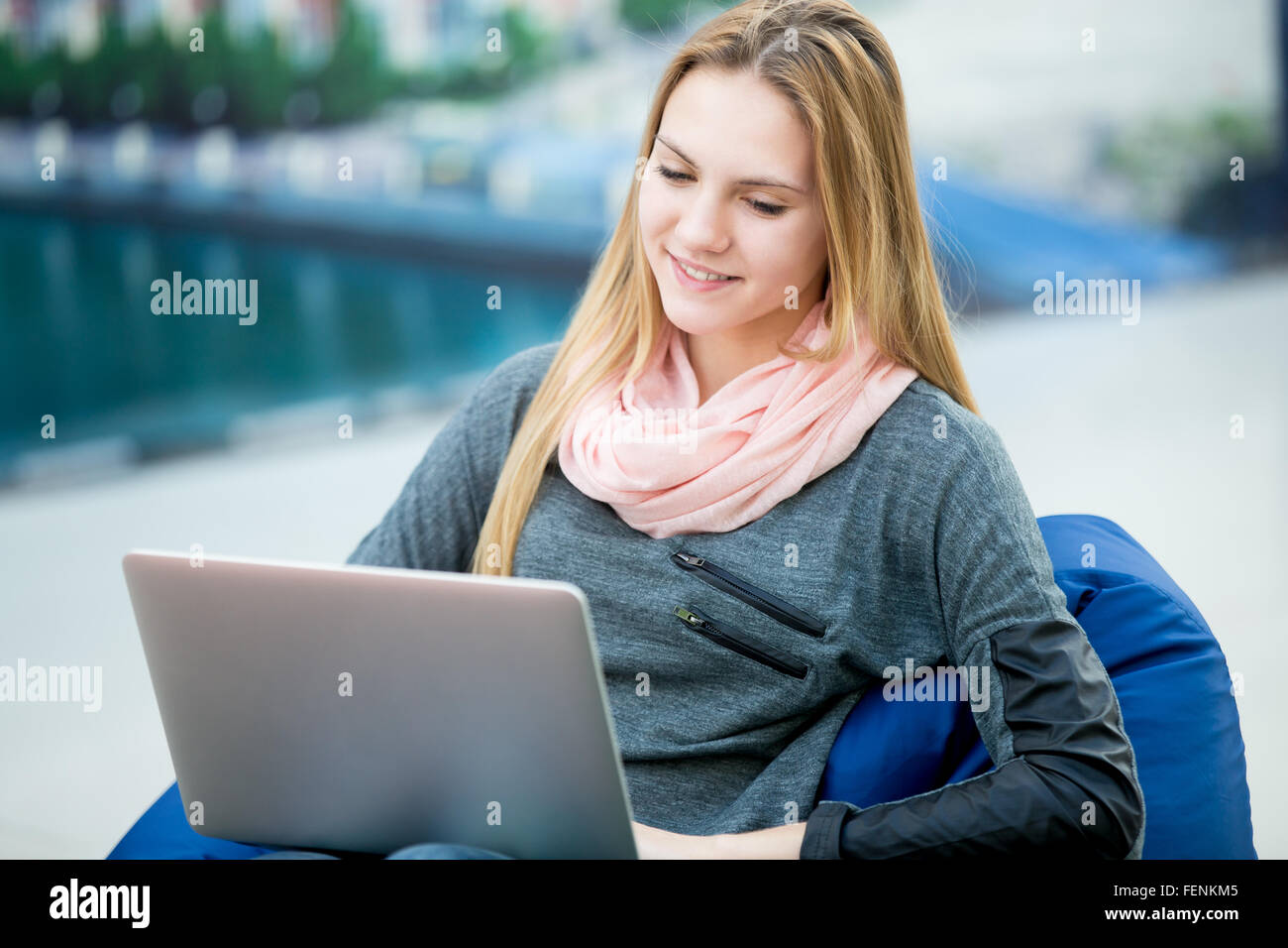 Entspannte junge Frau sitzen in bequemen Sitzsack mit Laptop, glücklich lächelnd, Online-shopping, Studium, arbeiten. Landschaft Stockfoto