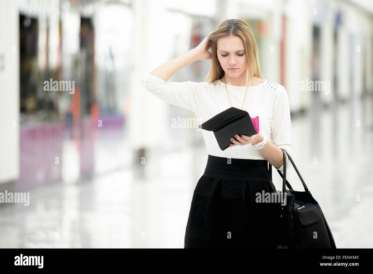 Unruhigen junge Frau, die ratlos in ihrer Brieftasche, Taschengeld, begrenztes Budget finanzieren Probleme, Exemplar Stockfoto