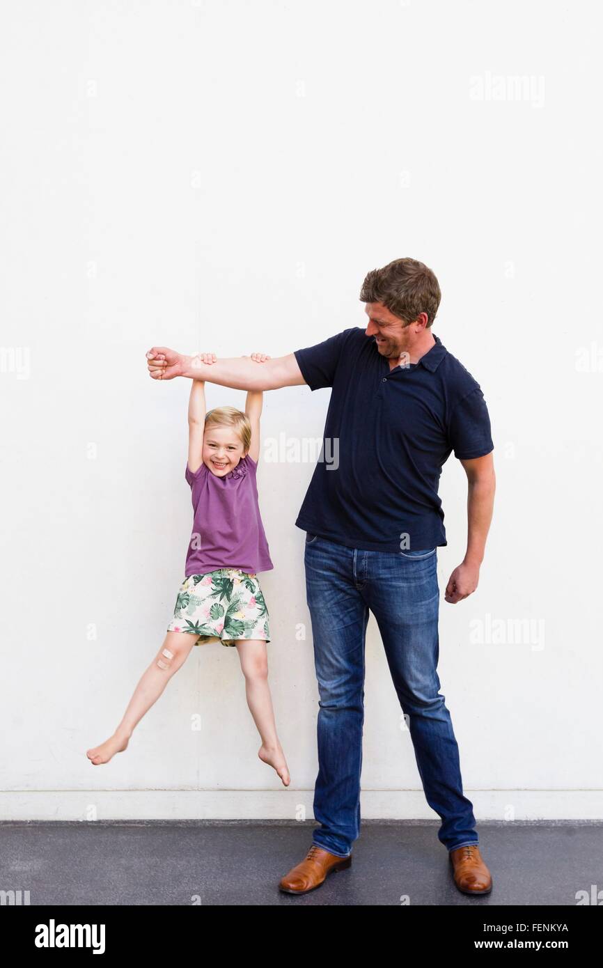 Porträt von reifer Mann mit Tochter von seinen Arm vor weißer Wand hängen Stockfoto