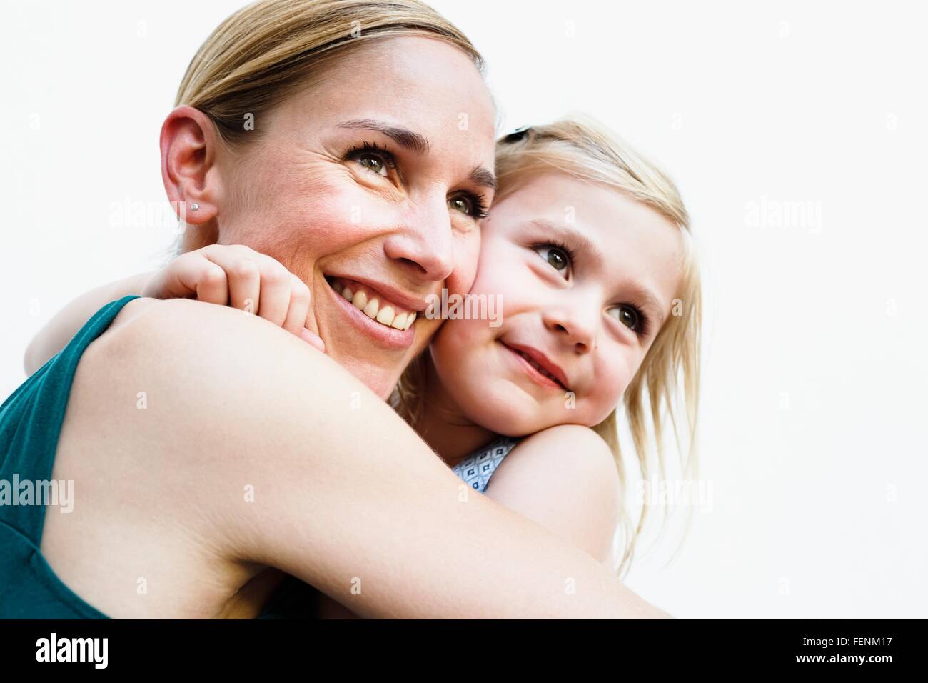 Porträt von Mitte Erwachsene Frau und Tochter umarmt vor weißer Wand Stockfoto