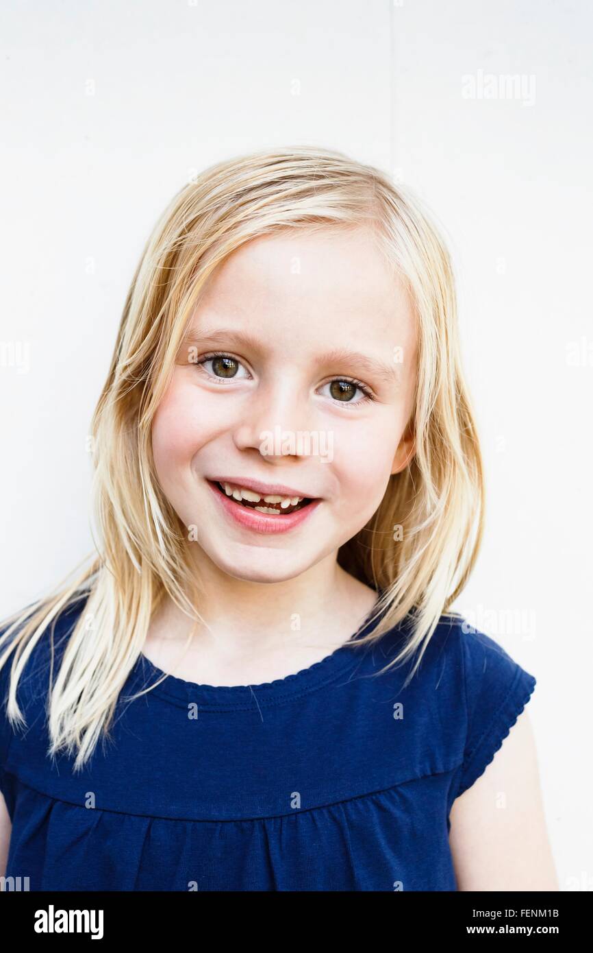 Porträt der niedliche Mädchen mit toothy Grinsen vor weißer Wand Stockfoto
