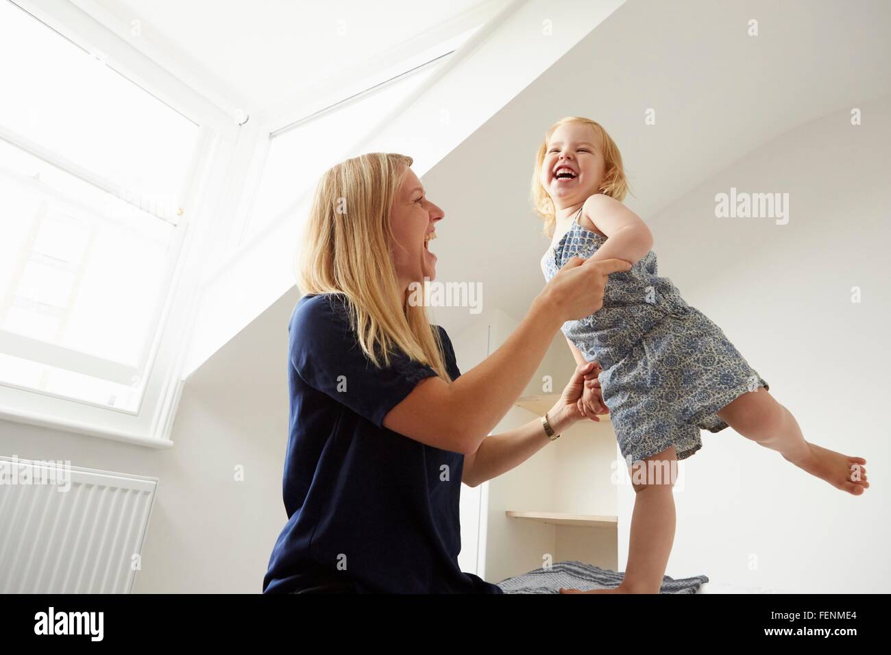 Mitte Erwachsene Frau und Kleinkind Tochter tanzen auf Bett Stockfoto