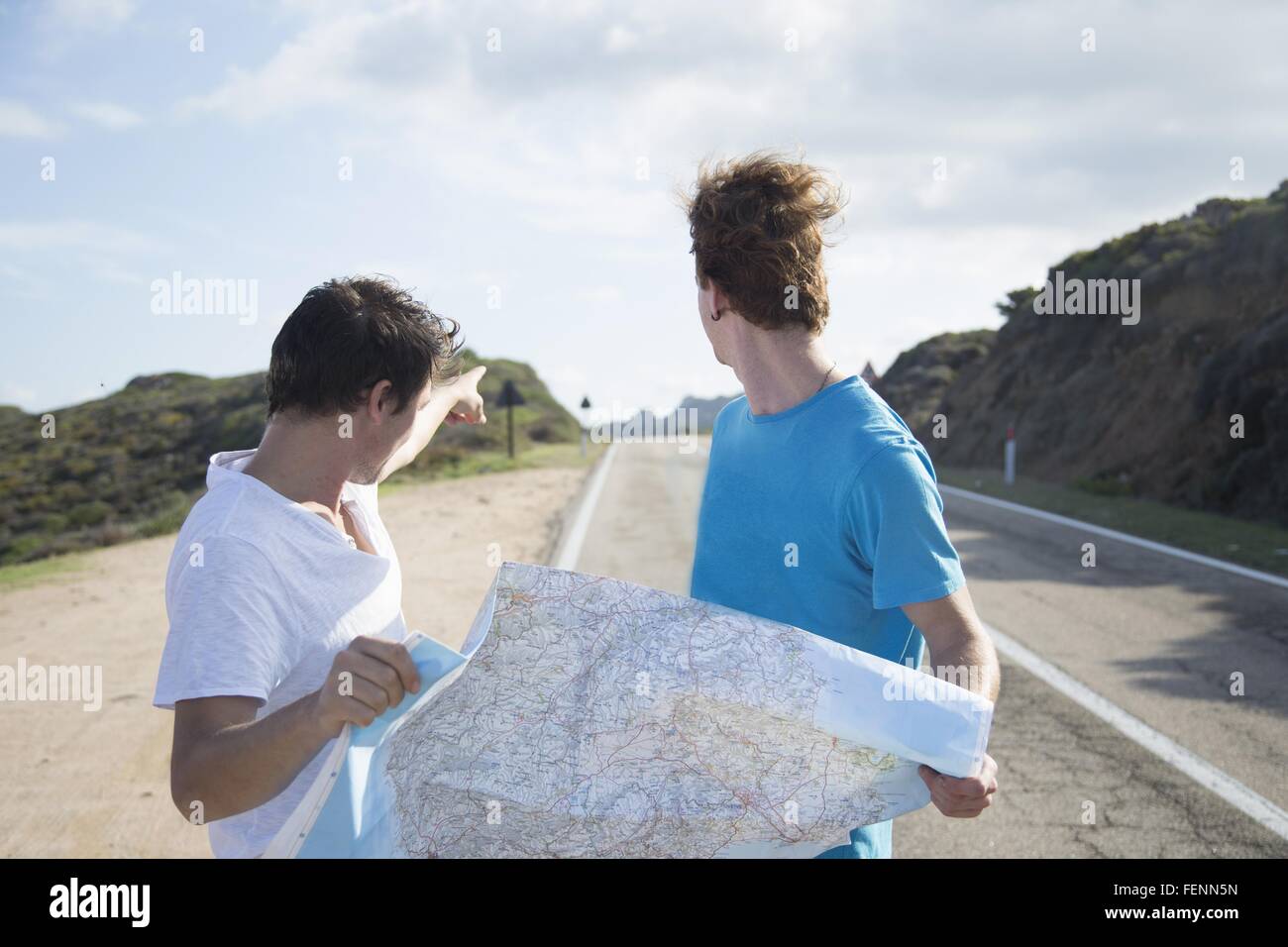 Junge Männer auf Straßenlage Karte, auf der Suche über die Schulter zeigend, Costa Smeralda, Sardinien, Italien Stockfoto