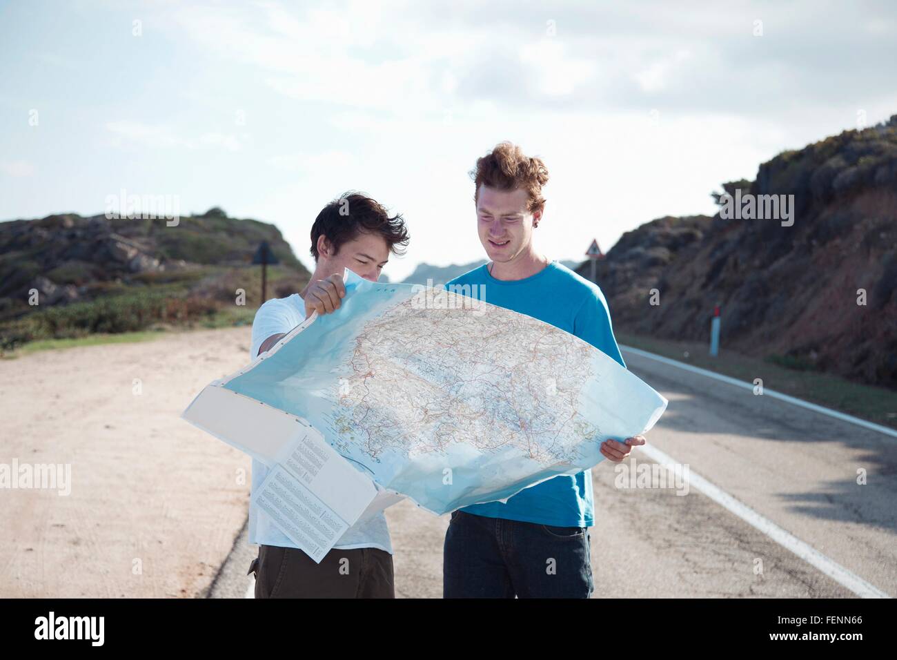 Junge Männer stehen auf Straße, Blick auf Karte lächelnd, Costa Smeralda, Sardinien, Italien Stockfoto