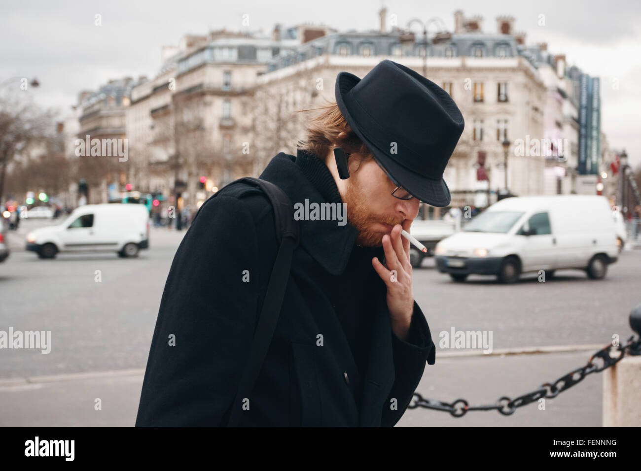 Nachdenklich bärtiger Mann mit Hut Rauchen auf der Straße in europäischen Stadt. Tiefenschärfe, Korn hinzugefügt. Stockfoto