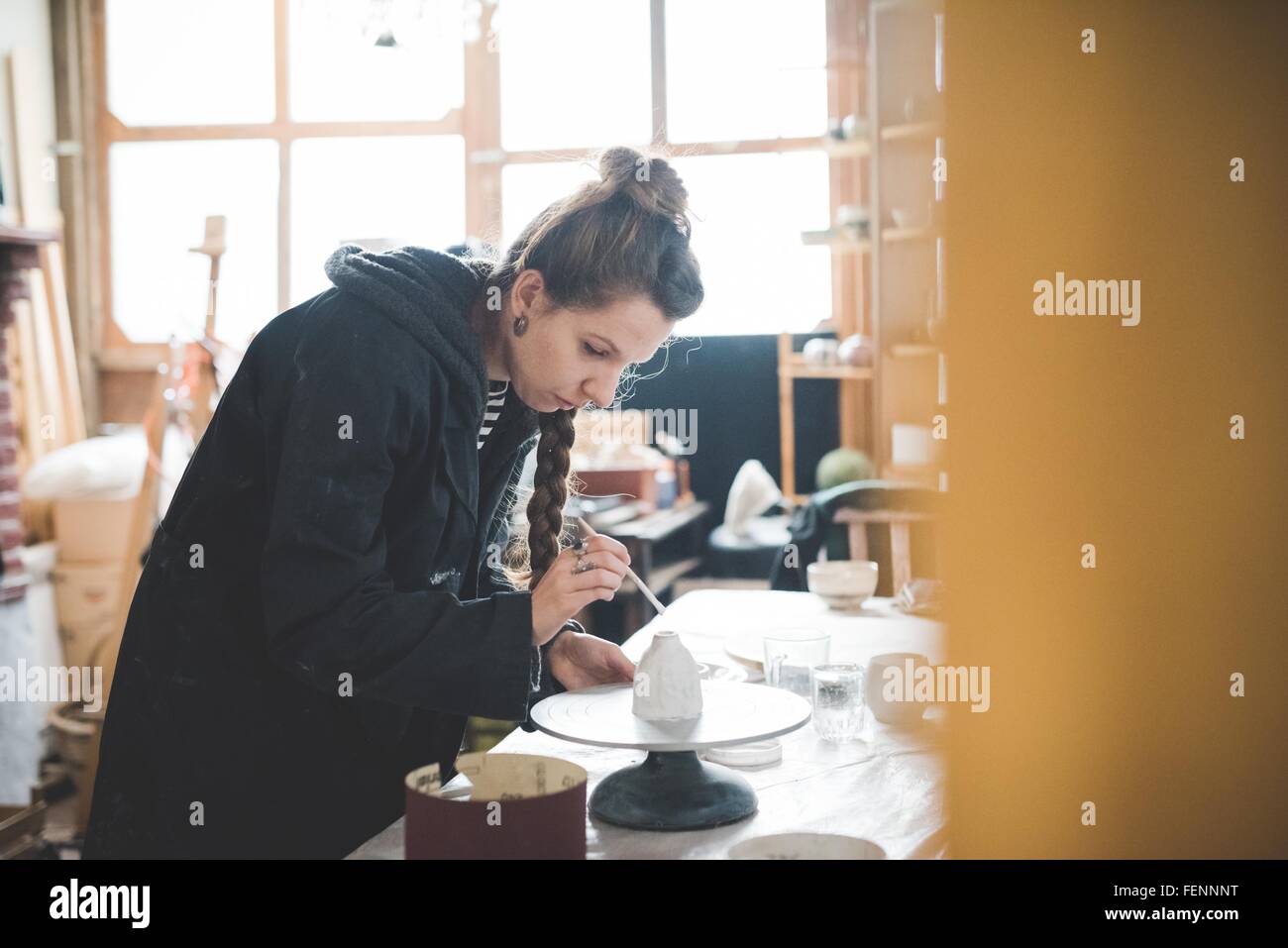 Seitenansicht der jungen Frau in Werkstatt Tontopf, Keramikglasur zuweisen blickte Stockfoto