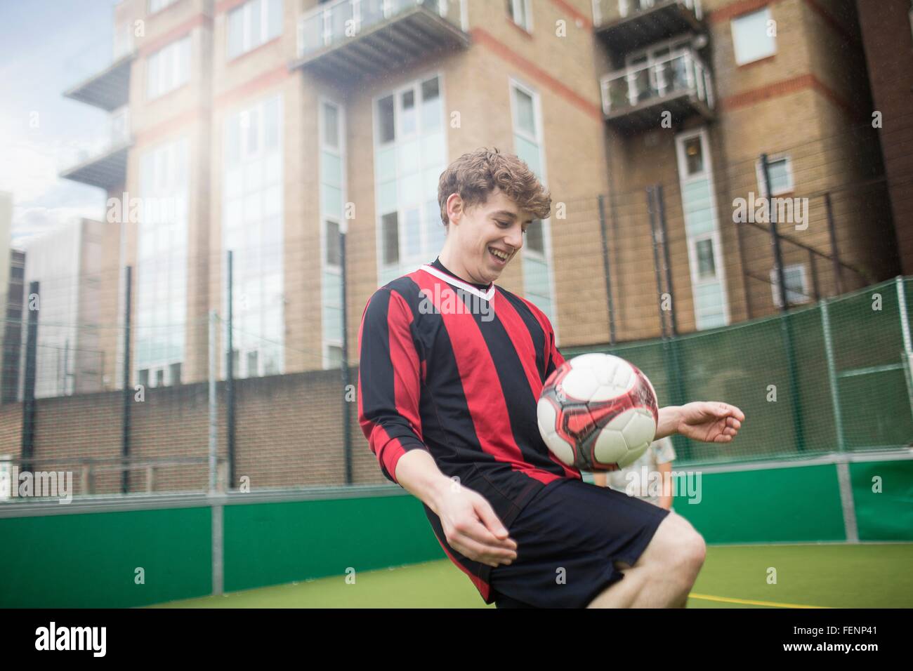 Junger Mann üben fußballerischen Fähigkeiten auf städtischen Fußballfeld Stockfoto