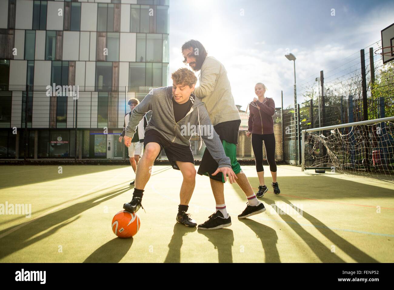 Gruppe von Erwachsenen, die Fußball spielen auf städtischen Fußballfeld Stockfoto